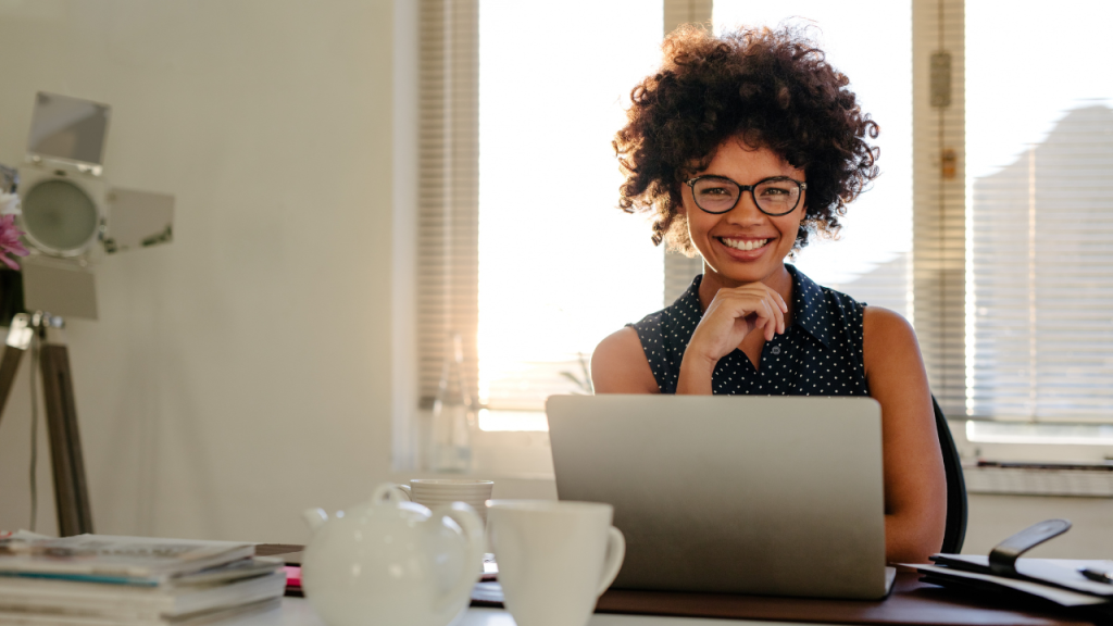 Mulher negra sorrindo em frente ao notebook